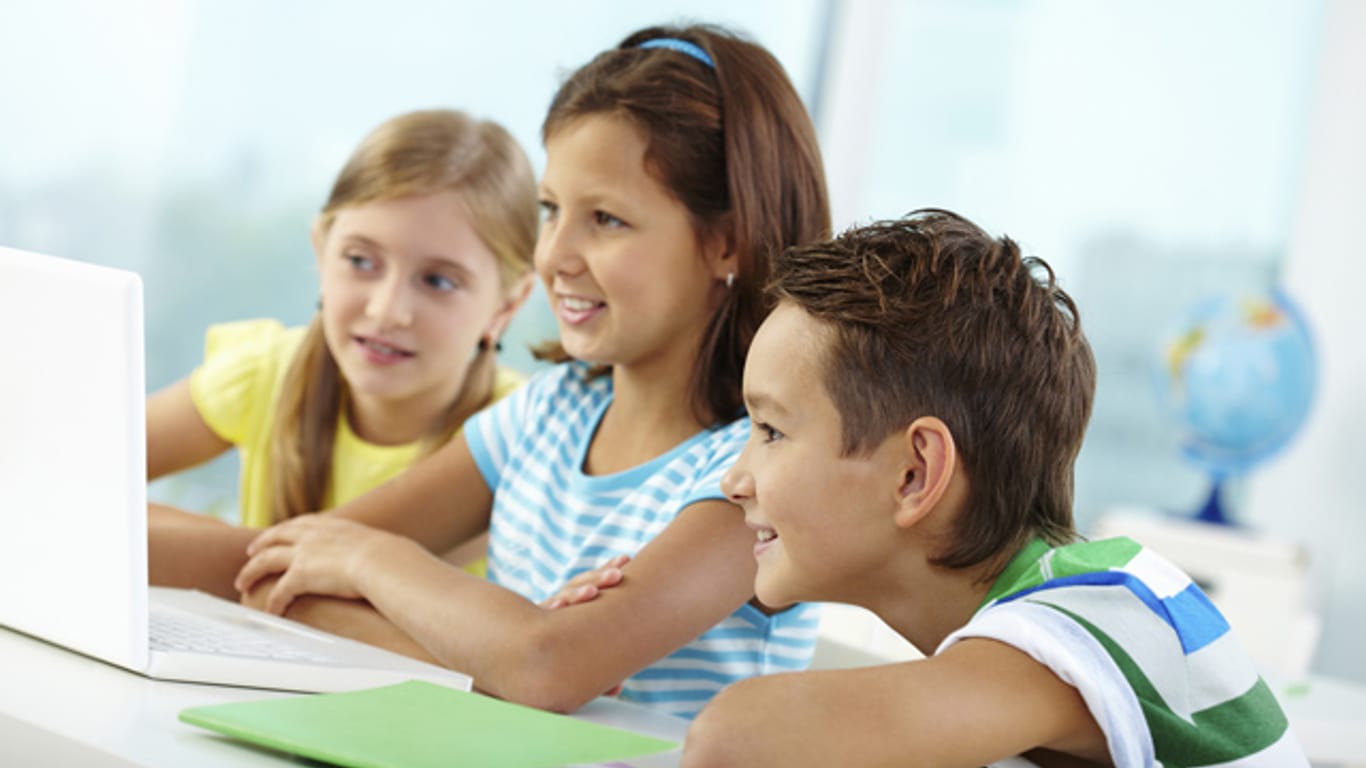 Drei Kinder sitzen vor einem Laptop: Künstliche Intelligenzen sind auch für Kinder zugänglich.