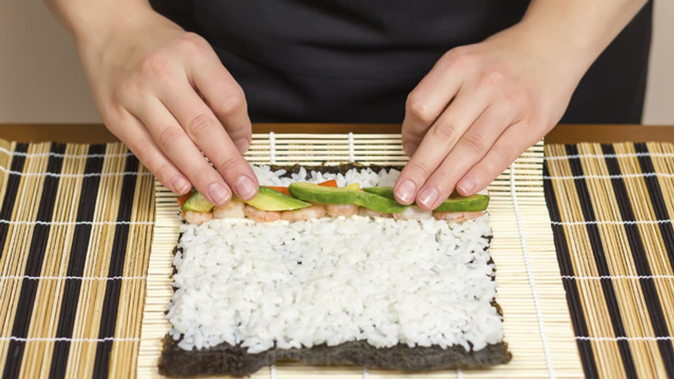 Rollen Sie das Maki-Sushi möglichst fest zusammen und verkleben Sie die Rolle zum Schluss