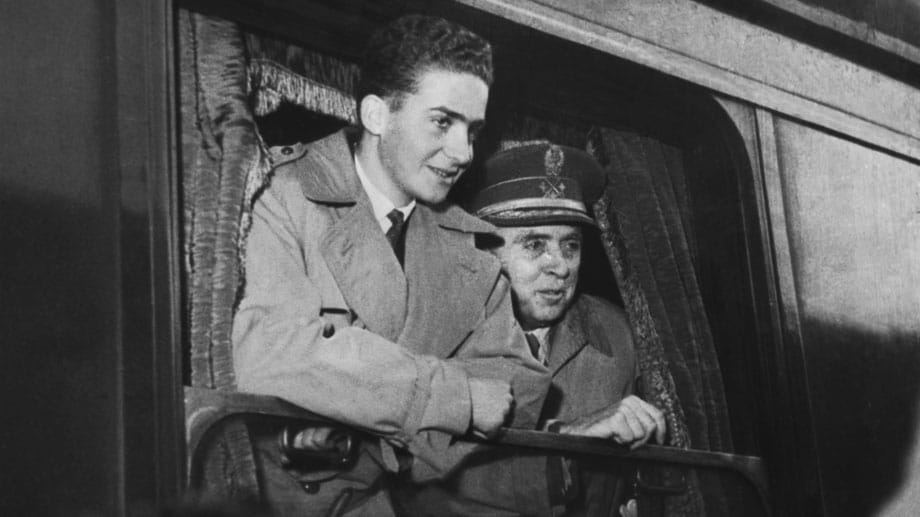 Längst vergangene Zeiten: Juan Carlos bei seiner Ankunft auf dem Bahnhof von Madrid im Januar 1955, neben ihm der Herzog de la Torre. Zu diesem Zeitpunkt war der heutige König noch im Teenager-Alter und gerade mal 17 Jahre jung.