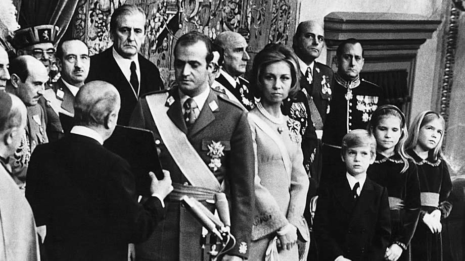 Juan Carlos (Mitte links) wird am 22.11.1975 in Madrid als neuer spanischer König vereidigt. Rechts daneben steht seine Frau Sofia mit den Kindern Prinz Felipe, Prinzessin Elena und Prinzessin Cristina (v. li.n.re.). Damit begann der Prozess des Übergangs zur Demokratie.