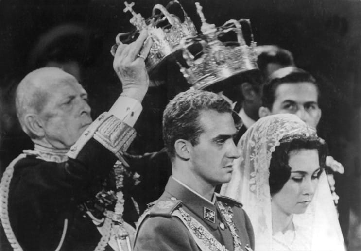 Das Brautpaar, Kronprinz Juan Carlos von Spanien und Prinzessin Sofia von Griechenland, während der Trauungszeremonie am 14. Mai 1962 in Athen. Links hält König Paul I. von Griechenland die Kronen über die Häupter des Paares.