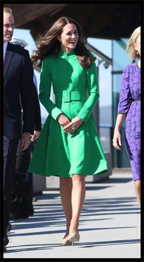 Kate in einem auffälligen grünen Mantel mit großer Schnalle.