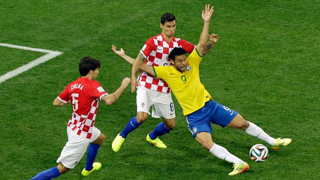 Brasiliens Nummer Neun Fred stürzt nach einem harmlosen Trikot-Zupfer von Dejan Lovren zu Boden.