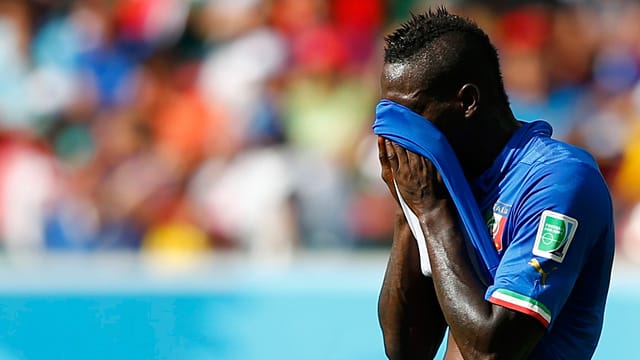Italiens Stürmerstar Mario Balotelli versteckt sein Gesichter hinter dem Trikot.