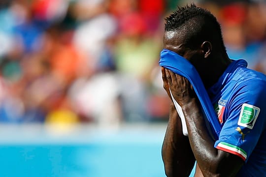 Italiens Stürmerstar Mario Balotelli versteckt sein Gesichter hinter dem Trikot.