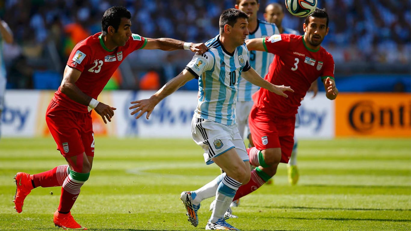Die Iraner Mehrdad Pooladi (li.) und Ehsan Hajsafi (re.) versuchen Argentiniens Lionel Messi (Mi.) zu stoppen.