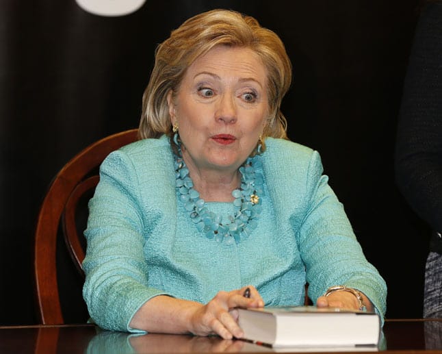 Oh, was haben wir denn da? Das scheint sich Hillary Clinton beim Anblick des Buches vor ihr zu denken. Herausgekommen ist dabei ein witziger Schnappschuss.