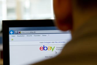 Ein Mann sitzt vor einem Bildschirm mit der eBay-Startseite.