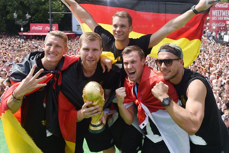 Bastian Schweinsteiger, Per Mertesacker, Manuel Neuer, Kevin Großkreutz und Lukas Podolski (v.l.n.r.) feiern auf der Berliner Fanmeile den Titelgewinn.