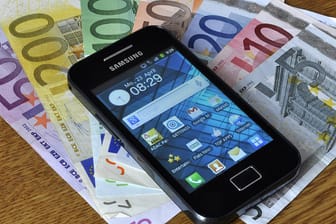 Smartphone liegt auf mehreren Euro-Scheinen.
