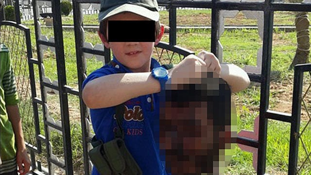 Das Dokument des Grauens: Der kleine Junge präsentiert den Kopf eines Getöteten. Das Dokument des Grauens: Der kleine Junge präsentiert den Kopf eines Getöteten.