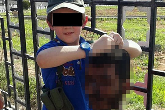 Das Dokument des Grauens: Der kleine Junge präsentiert den Kopf eines Getöteten.