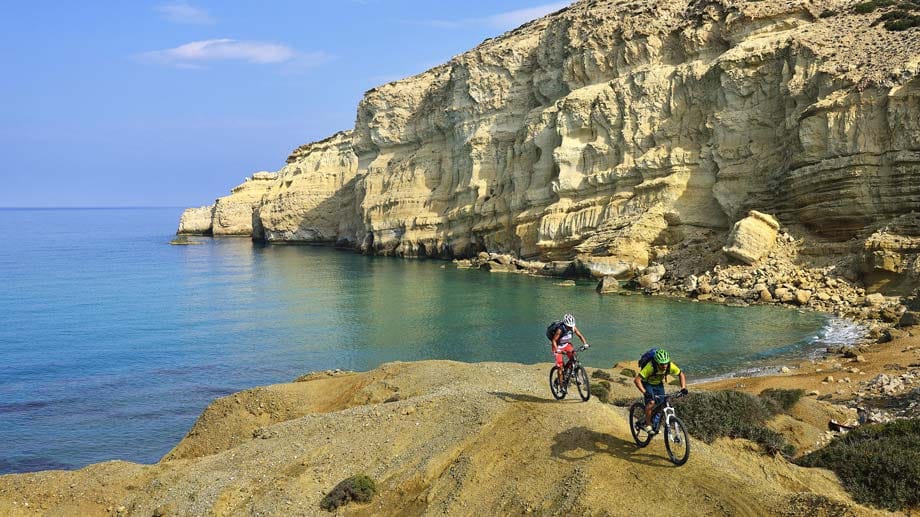 Mountainbiker am Red Beach von Matala auf Kreta: Auf der Insel ist es nie weit bis zur nächsten Badebucht.