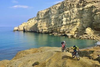 Mountainbiker am Red Beach von Matala auf Kreta: Auf der Insel ist es nie weit bis zur nächsten Badebucht.