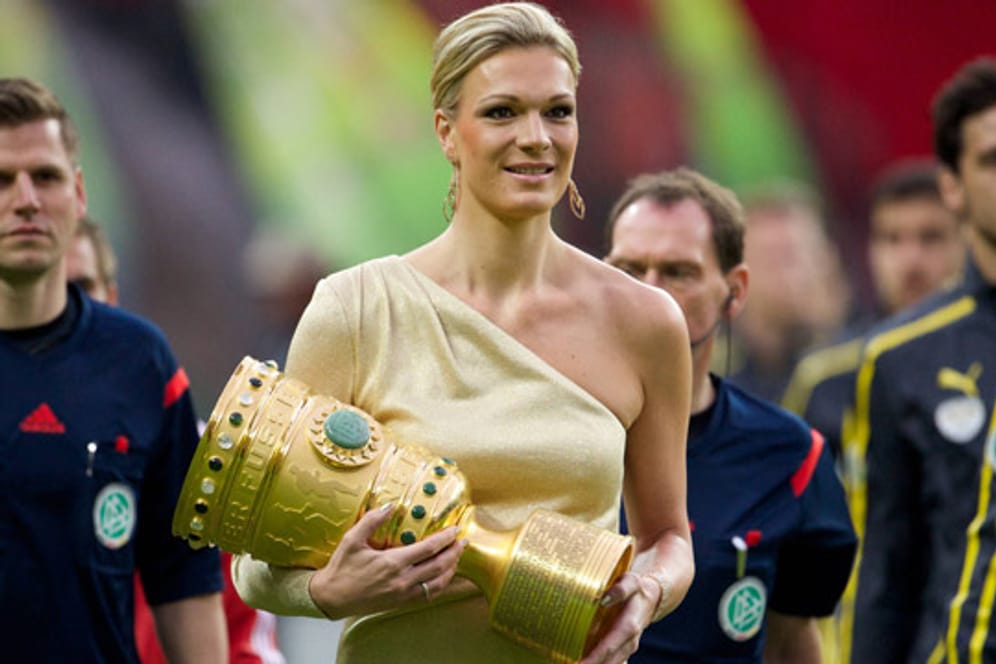 Ex-Ski-Star Maria Höfl-Riesch trägt den DFB-Pokal in die Arena.