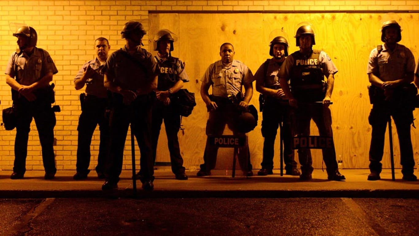 Neue Ausschreitungen vor der Ausgangssperre: Polizisten beobachten in der Kleinstadt Ferguson, wie sich Demonstranten formieren
