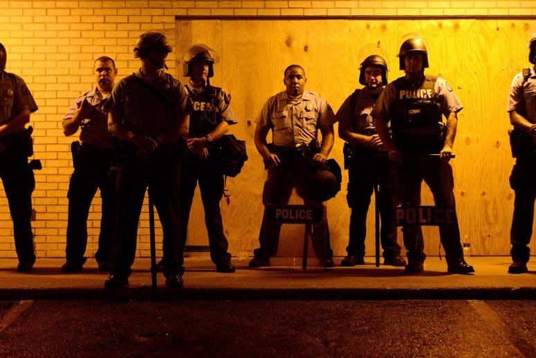 Neue Ausschreitungen vor der Ausgangssperre: Polizisten beobachten in der Kleinstadt Ferguson, wie sich Demonstranten formieren