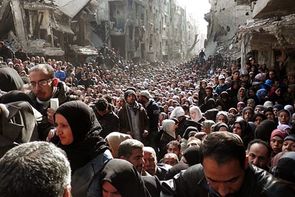 Flüchtlinge auf einer zerstörten Straße in Damaskus