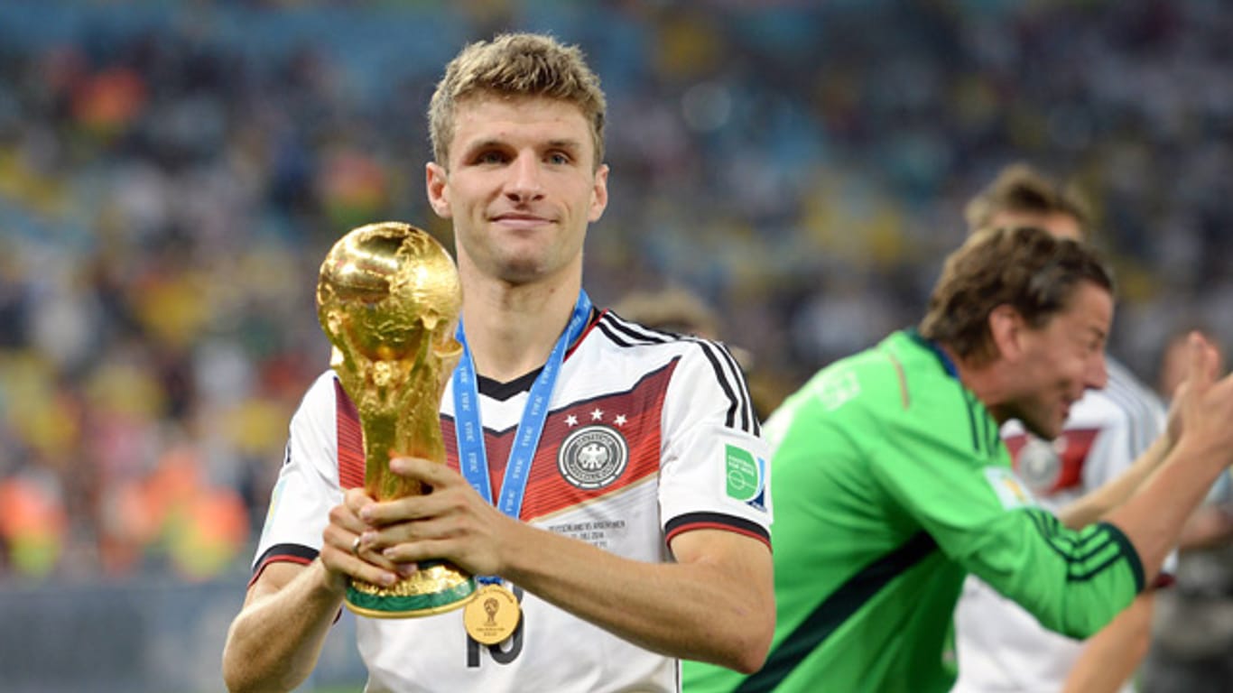 Thomas Müller hält den WM-Pokal in den Händen.