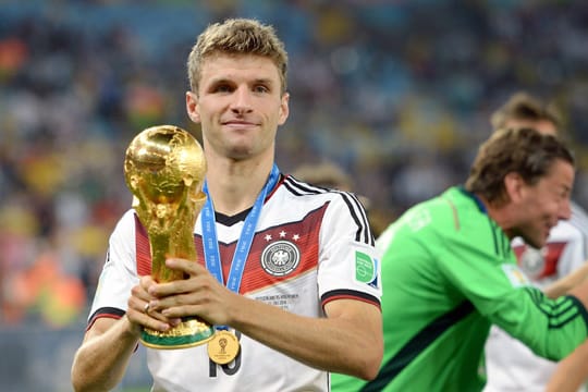 Thomas Müller hält den WM-Pokal in den Händen.