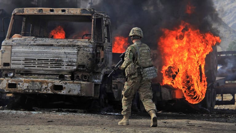 Ein US-Soldat steht in Afghanistan vor den ausgebrannten Trümmern eines Lkw.