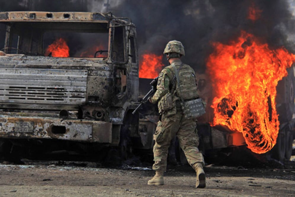 Ein US-Soldat steht in Afghanistan vor den ausgebrannten Trümmern eines Lkw.