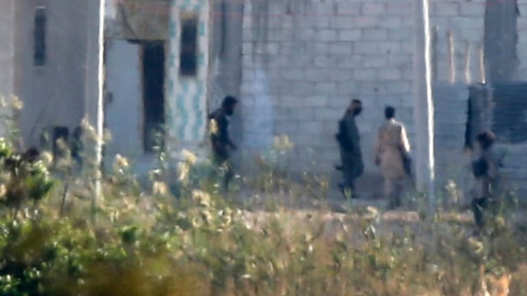 Kämpfer - vermutlich des IS - schleichen durch einen Außenbezirk von Kobane