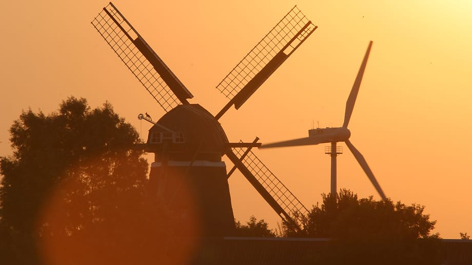 Windkraft gestern und heute: In Ostfriesland stehen historische Windmühlen und hochmoderne Windkraftanlagen einträchtig nebeneinander. Fürs Urlaubsfoto geben die alten Mühlen mehr her, aber…
