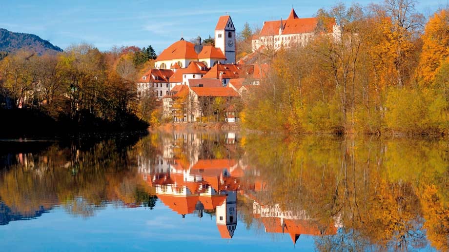 Blick über den Lech auf Füssen im Herbst - im Hintergrund sieht man unter anderem das Kloster St. Mang.