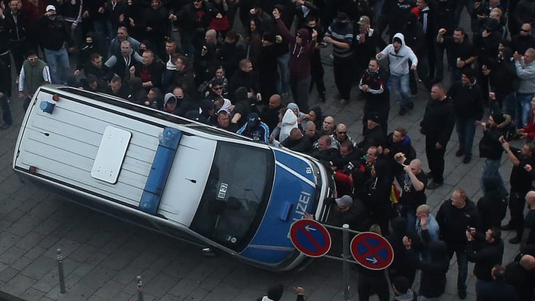 Demonstranten werfen am 26.10.2014 in Köln ein Polizeiauto um. Bei den Ausschreitungen kam es zu zahlreichen Verletzten.