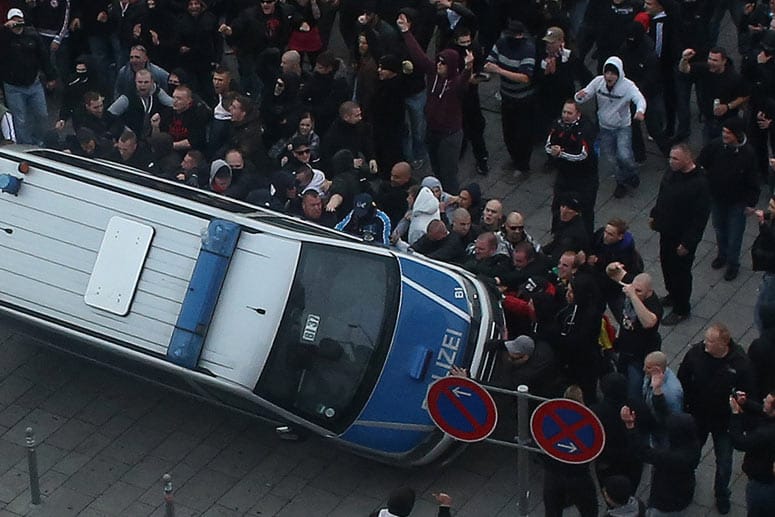 Demonstranten werfen am 26.10.2014 in Köln ein Polizeiauto um. Bei den Ausschreitungen kam es zu zahlreichen Verletzten.