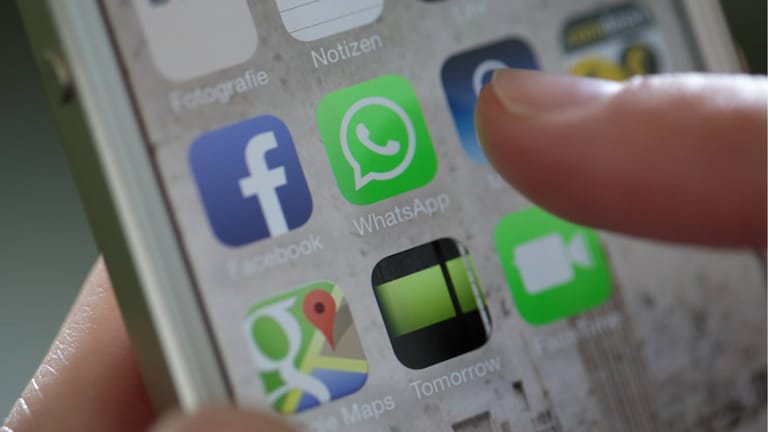 Junge Frau öffnet WhatsApp auf einem iPhone