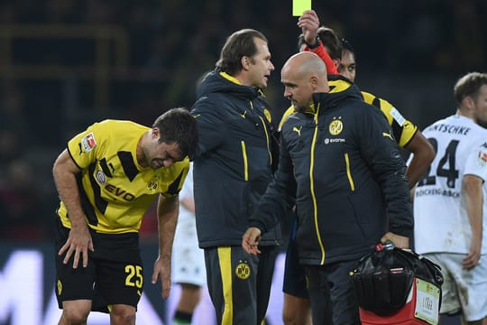 Sokratis (li.) humpelt verletzt vom Feld und bekommt von Schiedsrichter Felix Brych die Gelbe Karte gezeigt.