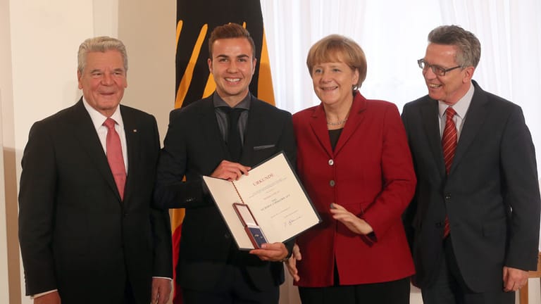 Mario Götze (2.v.li.) ist sichtlich stolz auf seine Auszeichnung. Bundespräsident Joachim Gauck, Bundeskanzlerin Angela Merkel und Innenminister Thomas de Maizière freuen sich mit dem Weltmeister.