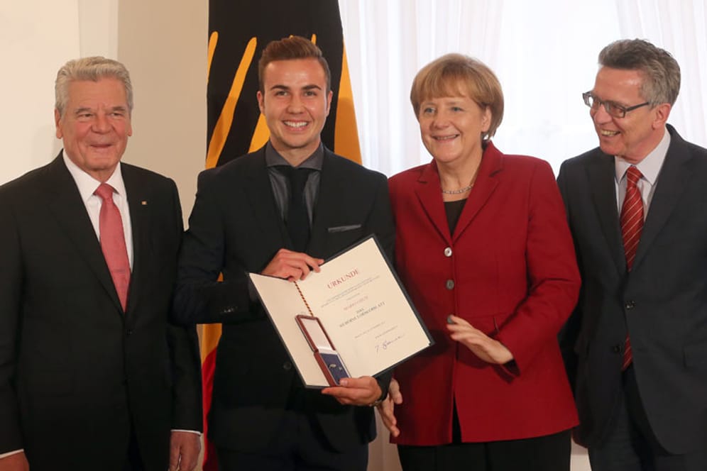 Mario Götze (2.v.li.) ist sichtlich stolz auf seine Auszeichnung. Bundespräsident Joachim Gauck, Bundeskanzlerin Angela Merkel und Innenminister Thomas de Maizière freuen sich mit dem Weltmeister.