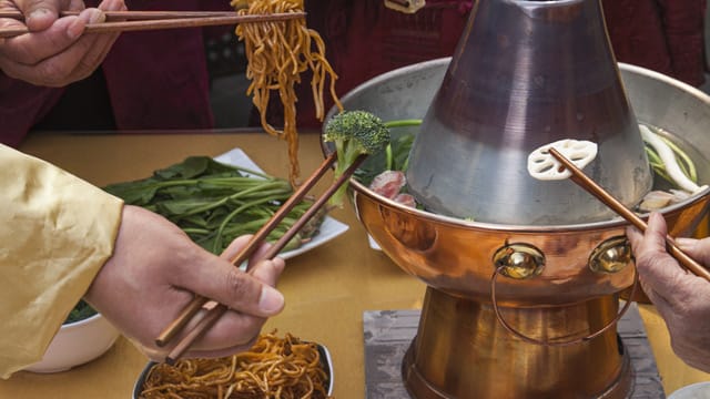 Chinesisches Fondue funktioniert wie klassisches Fondue mit Öl: Sie garen verschiedene Zutaten in einer leckeren Brühe.