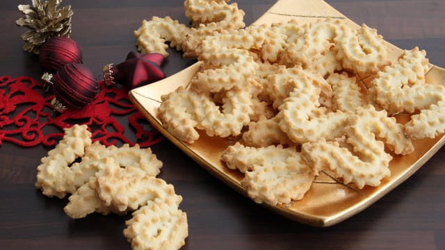 Die fertigen Plätzchen können Sie mit Schokolade überziehen oder mit Zuckerguss und Zuckerperlen verzieren