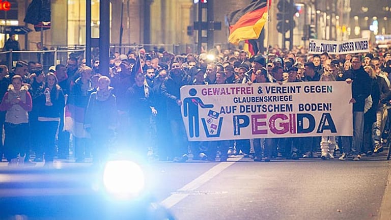 Teilnehmer einer Demonstration des Bündnisses Pegida laufen mit Transparenten durch die Dresdner Innenstadt