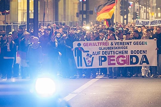 Teilnehmer einer Demonstration des Bündnisses Pegida laufen mit Transparenten durch die Dresdner Innenstadt