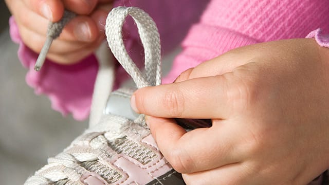 Eine Schleife zu binden, dauert länger als einen Klettverschluss zu schließen. Doch Eltern sollten sich und ihren Kindern diese Zeit gönnen.