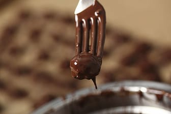 Mozartkugeln werden mit geschmolzener Schokolade überzogen