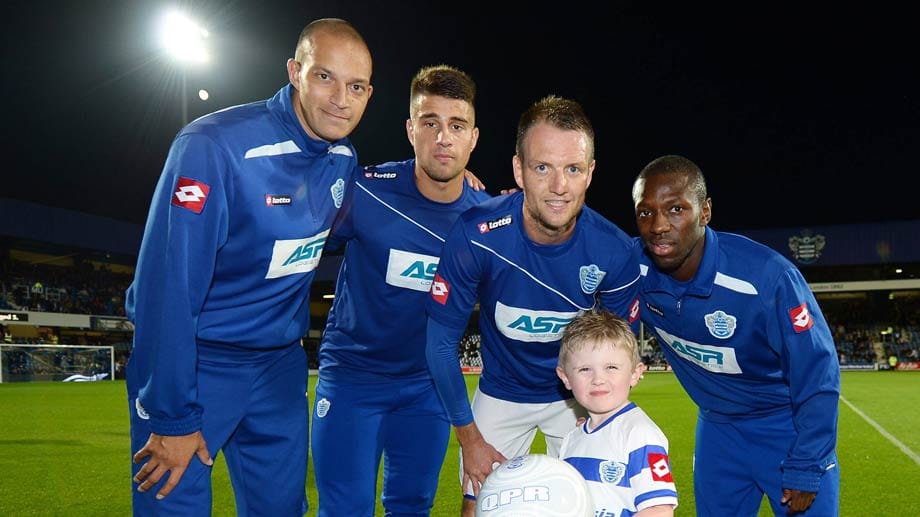 Ein Einlaufkind ist beim Foto mit Profis von den Queens Park Rangers überglücklich.