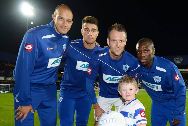 Ein Einlaufkind ist beim Foto mit Profis von den Queens Park Rangers überglücklich.