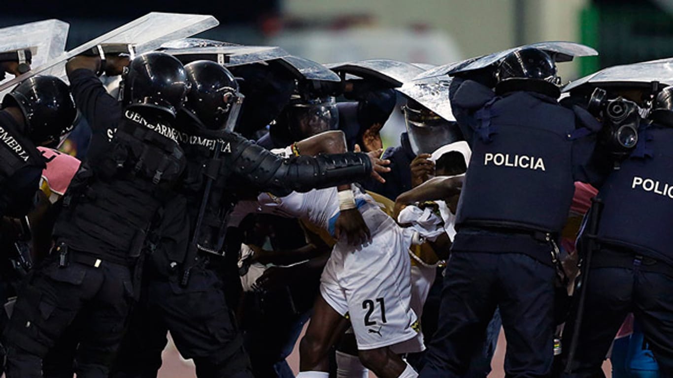 Polizisten müssen die Spieler Ghanas vor Wurfgeschossen schützen.