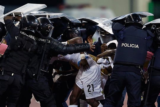 Polizisten müssen die Spieler Ghanas vor Wurfgeschossen schützen.