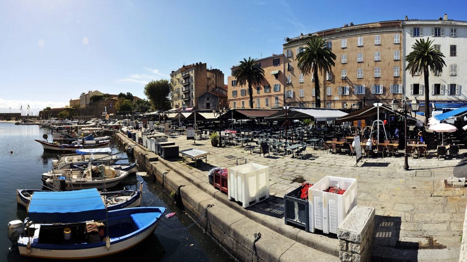 Ajaccio: Blick auf den Quai Napoleon und Teile des Sportboothafens. Dicht an dicht stehen die Tische und Bänke der Cafés und Restaurants entlang der Kaimauer.