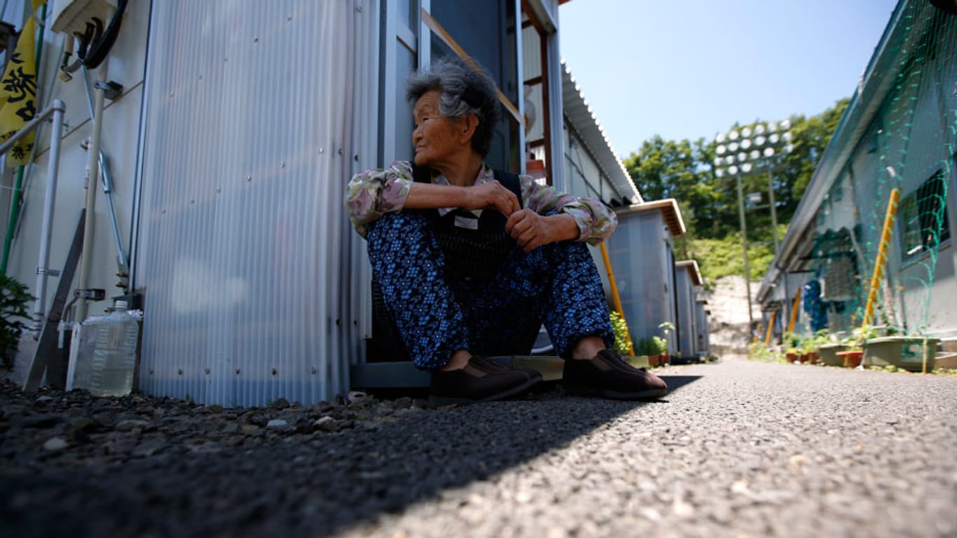 Eine alte Frau sitzt vor ihrer provisorischen Unterkunft in Kawamata. Tausende Japaner können auch vier Jahre nach der Katastrophe in Japan nicht zurück in ihre Heimat.