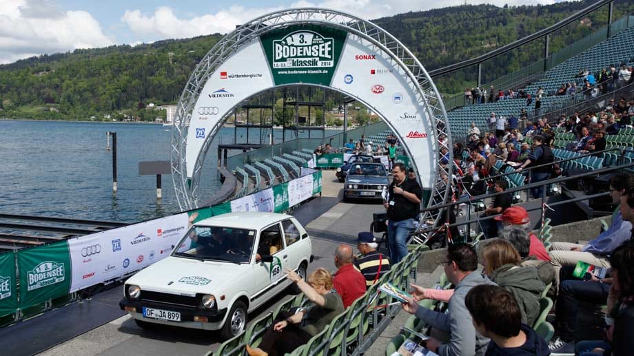 Jede Oldtimer-Rallye hat ihren eigenen Charakter, hier die Bodensee-Klassik, bei der gerade ein Suzuki Alto über die Startlinie in Bregenz fährt.