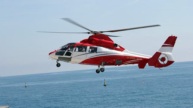 Ein Eurocopter Dauphin AS 365 N der Heli Air Monaco beim Flug über das Meer.