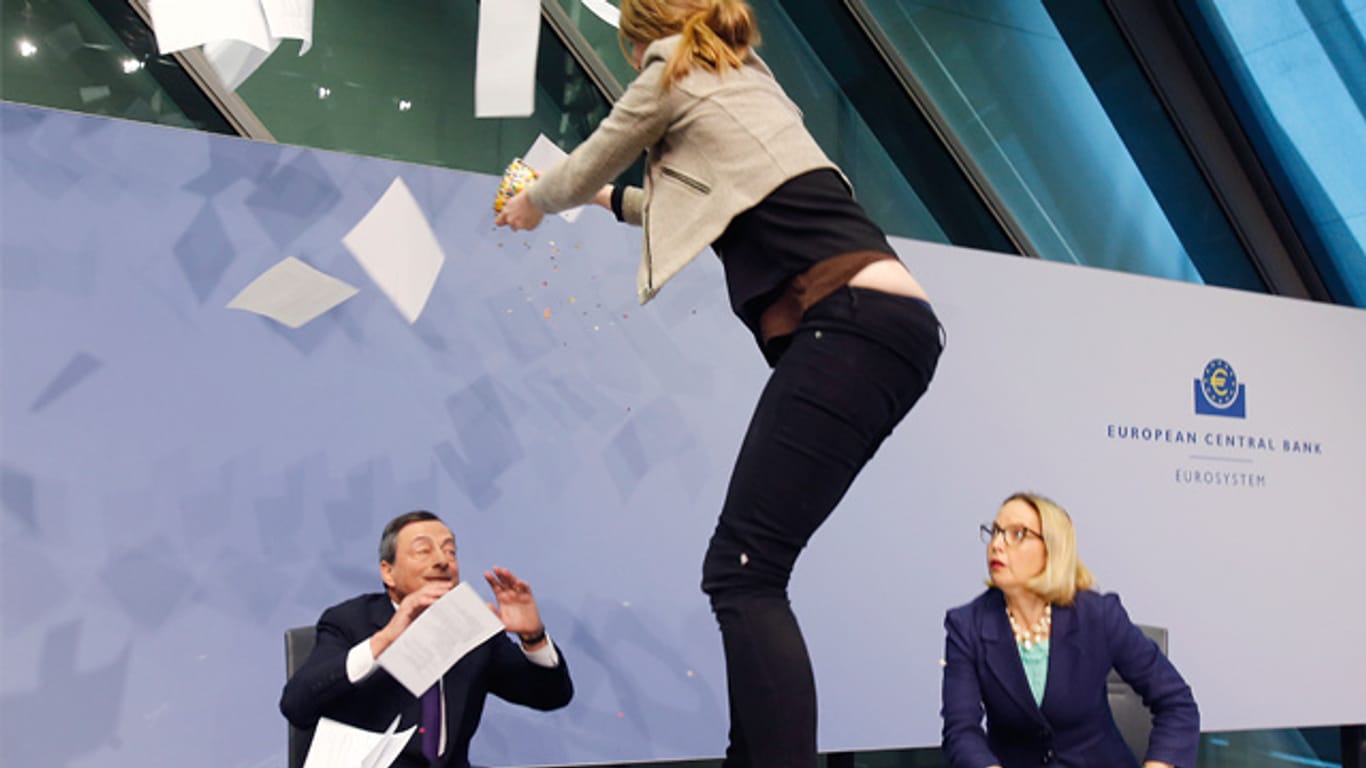 Eine Aktivistin springt vor EZB-Präsident Mario Draghi auf den Tisch.